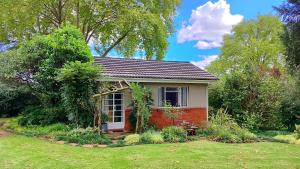 a small red and white house in a yard at Willowlea Cottage in Underberg