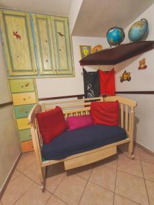 a wooden couch with two red pillows in a room at Casa Magnolia in Galtellì +5 photos