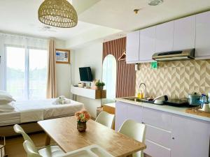 Casa Diana Pine Suites Tagaytay, Free Wi-Fi في تاجيتاي: غرفة بسرير ومطبخ مع طاولة