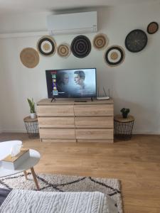 a living room with a tv on a wooden dresser at The Grey studio in Saint-Michel-sur-Orge