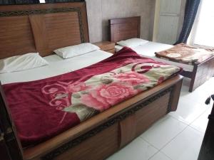 two beds in a hotel room with a red blanket at Buttkarahi Hotel And Restaurant in Dargai