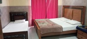 a bedroom with two beds and a pink curtain at Buttkarahi Hotel And Restaurant in Dargai