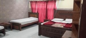 two beds in a room with red curtains at Buttkarahi Hotel And Restaurant in Dargai
