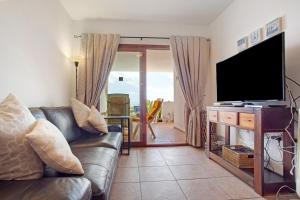 a living room with a couch and a flat screen tv at Casa Rosa in Costa Teguise