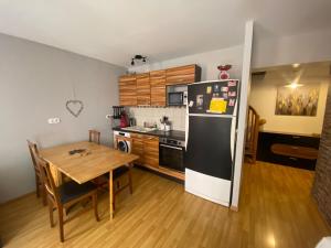 a kitchen with a table and a black refrigerator at Duplex 60m2 vieux centre avec balcon in Barcelonnette +7 photos