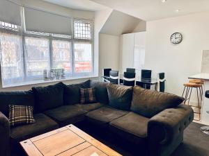 a living room with a brown couch and some windows at High Street Duplex 3 Bed Flat in Staines