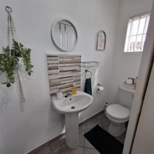 a white bathroom with a sink and a toilet at Sleep Haven Self-Catering Accommodation - Nelspruit in Nelspruit +23 photos