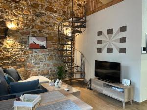 a living room with a stone wall and a tv at Downtown ViAlla in Chios
