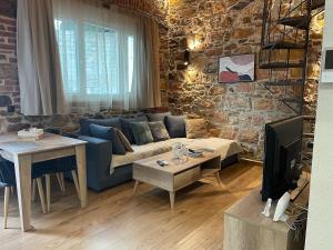 a living room with a blue couch and a stone wall at Downtown ViAlla in Chios