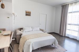 a white bedroom with a bed and a desk at Maya Bay Suites in Alicante +32 photos