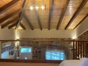 a bedroom with wooden ceilings and a brick wall at Downtown ViAlla in Chios