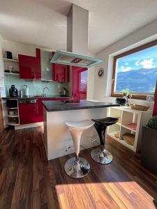a kitchen with red cabinets and a bar with a stool at Apart Spieljochbahn in Fügenberg