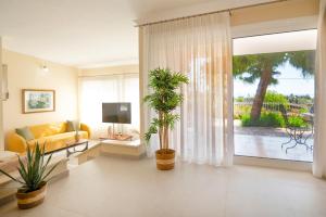カト・コラキアナにあるVilla Marifeiの黄色いソファと2つの植物があるリビングルーム