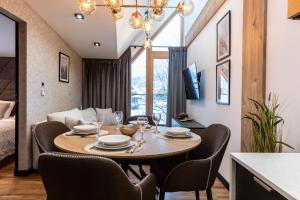 a dining room with a table and chairs and a couch at APARTAMENT przy stoku Białka Tatrzańska Spa & Resort in Białka Tatrzanska