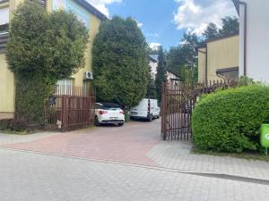 un cancello che dà su un vialetto con auto parcheggiate su una strada di Fałata pokoje a Kobyłka