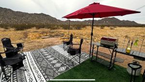 einen Grill auf einer Terrasse mit Stühlen und einem Sonnenschirm in der Unterkunft Remote Modern Tiny House with Deck, BBQ and Mountain Views in Arizona in Maricopa