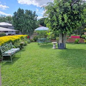 a yard with chairs and a tree and an umbrella at Sleep Haven Self-Catering Accommodation - Nelspruit in Nelspruit