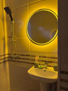 a yellow bathroom with a sink and a mirror at Hotel Sataplia in Banoja