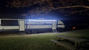 un rimorchio blu e bianco parcheggiato in un parco di notte di Cozy Equipped Camper With Picnic Space, Pool and BBQ in Virginia a Diggs
