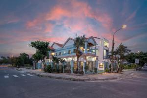 ディエン・バンにあるBlue Ocean Villa Hoi An - Ha Myの通りの前にヤシの木が茂る白い大きな建物