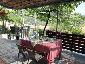 Stathis & Maria's Traditional House في Katokhórion: طاولة مع مفرش طاولة وردي وكراسي على الفناء