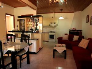 Stathis & Maria's Traditional House في Katokhórion: غرفة معيشة مع أريكة حمراء ومطبخ