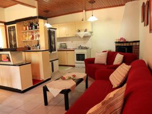 Stathis & Maria's Traditional House في Katokhórion: غرفة معيشة مع أريكة حمراء ومطبخ +9 صور