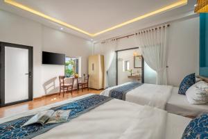 ディエン・バンにあるBlue Ocean Villa Hoi An - Ha Myのベッド2台とテーブルがあるホテルの部屋