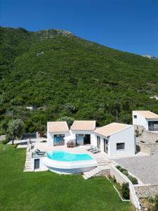 a house with a swimming pool in front of a hill at Tempestini Exclusive Villas in Nikiana