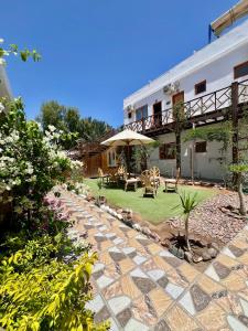 a garden with a patio with a table and an umbrella at Tree House Hotel Dahab in Dahab