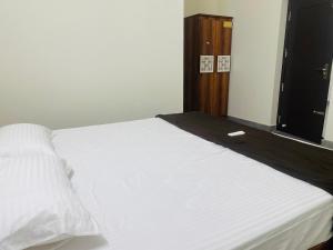 a bedroom with a white bed with a wooden cabinet at Yogi Ram Guest House in Tiruvannāmalai +4 photos