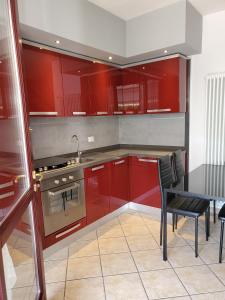 a kitchen with red cabinets and a table and a stove at Villetta Imola in Lido degli Estensi
