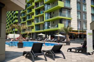 a hotel with a pool and chairs and a building at Sery Apartment Resort Alz in Mamaia Sat/Năvodari