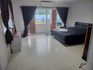 a bedroom with a bed and a large window at the three pyramids in Rawai Beach