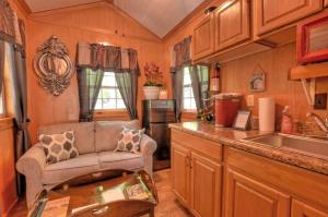 ein Wohnzimmer mit Couch und Küche in der Unterkunft Tiny House for Two with Outdoor Tub near Great Smoky Mountains in Cherokee, North Carolina in Cherokee