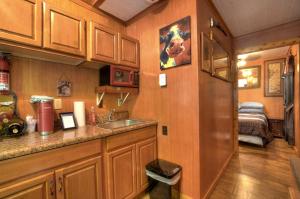eine Küche mit Holzschränken und einem Waschbecken sowie ein Schlafzimmer in der Unterkunft Tiny House for Two with Outdoor Tub near Great Smoky Mountains in Cherokee, North Carolina in Cherokee