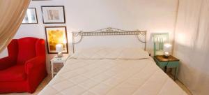 a bedroom with a white bed and a red chair at La Corte delle Arti in Matino