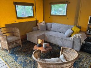 a living room with a couch and chairs and a table at Glampingtent Grou in Grou