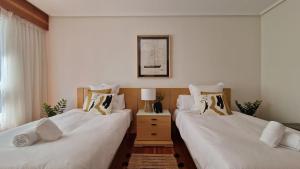 two beds in a bedroom with white sheets and pillows at VISTAS MAR Y PUERTO Plentzia - 200m2 y Parking in Plentzia