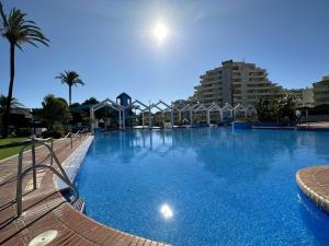 ein großes Schwimmbecken mit blauem Wasser und Gebäuden in der Unterkunft Benalbeach con vistas al mar in Arroyo de la Miel