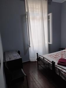 a bedroom with a bed and a window and a chair at Apartment Atiki metro shared bathroom and kitchen in Athens