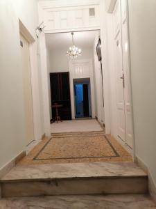 a hallway with white walls and a chandelier at Apartment Atiki metro shared bathroom and kitchen in Athens
