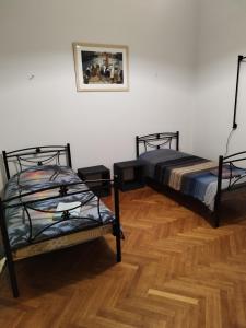 two beds in a room with a wooden floor at Apartment Atiki metro shared bathroom and kitchen in Athens