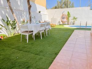 a table and chairs on a lawn with a pool at Chalet Relax con Piscina privada in Águilas