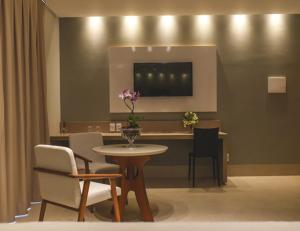 a dining room with a table and chairs and a table with flowers at Hotel D'Leon in Gurupi