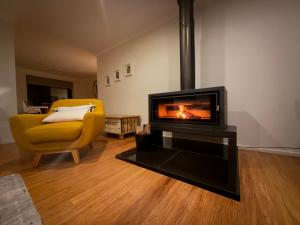 a living room with a fireplace and a yellow chair at Costa Casa Jervis Bay Retreat in Vincentia