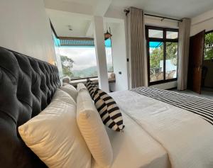 a bedroom with a large white bed with pillows at Fern Hill Cabins in Ella