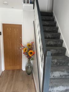 a vase of flowers in a hallway with stairs at Camaraderie Guest House in York