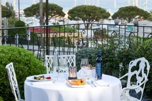 a white table with food and a bottle of wine at Hôtel L'Abbaye in Calvi