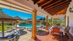 eine Außenterrasse mit Tischen und Stühlen sowie einem Pool in der Unterkunft Casa Senorio del Olivar Mijas by Ruralidays in Mijas